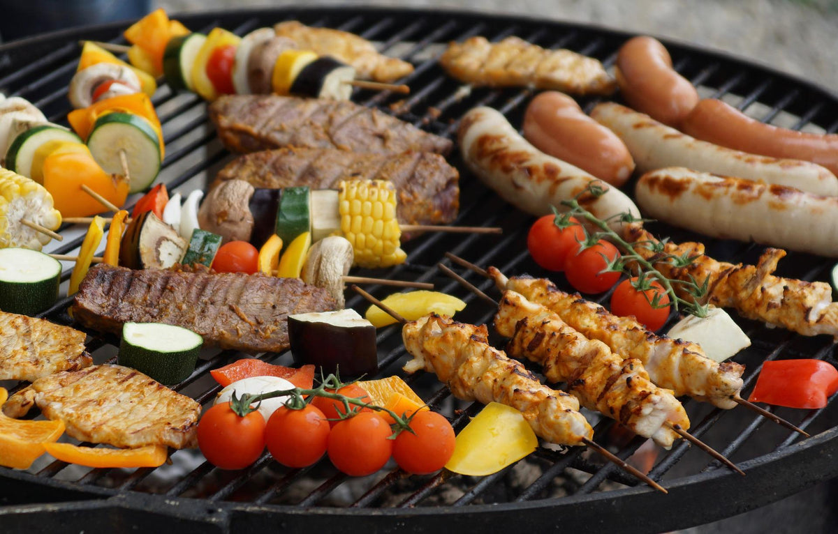 A spread of meat and vegetables cooking over a backyard fire pit