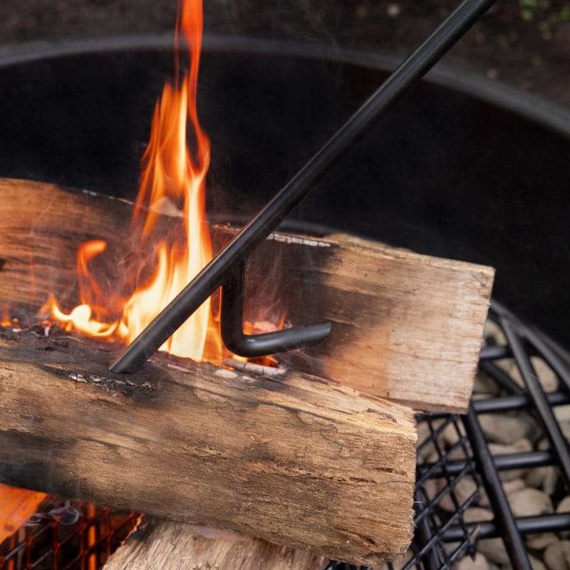 Walden Legacy Series Fire Poker poking firewood inside a fire pit ring