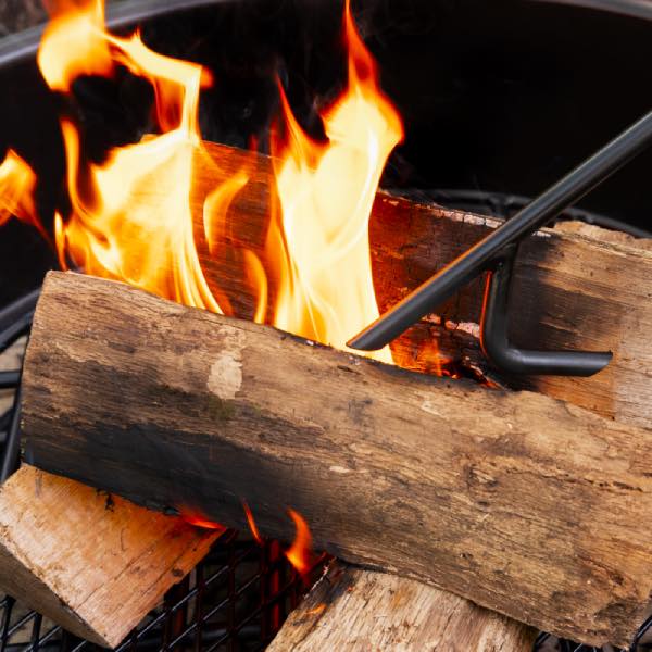 Walden Legacy Fire Poker adjusting a log inside a fire pit ring