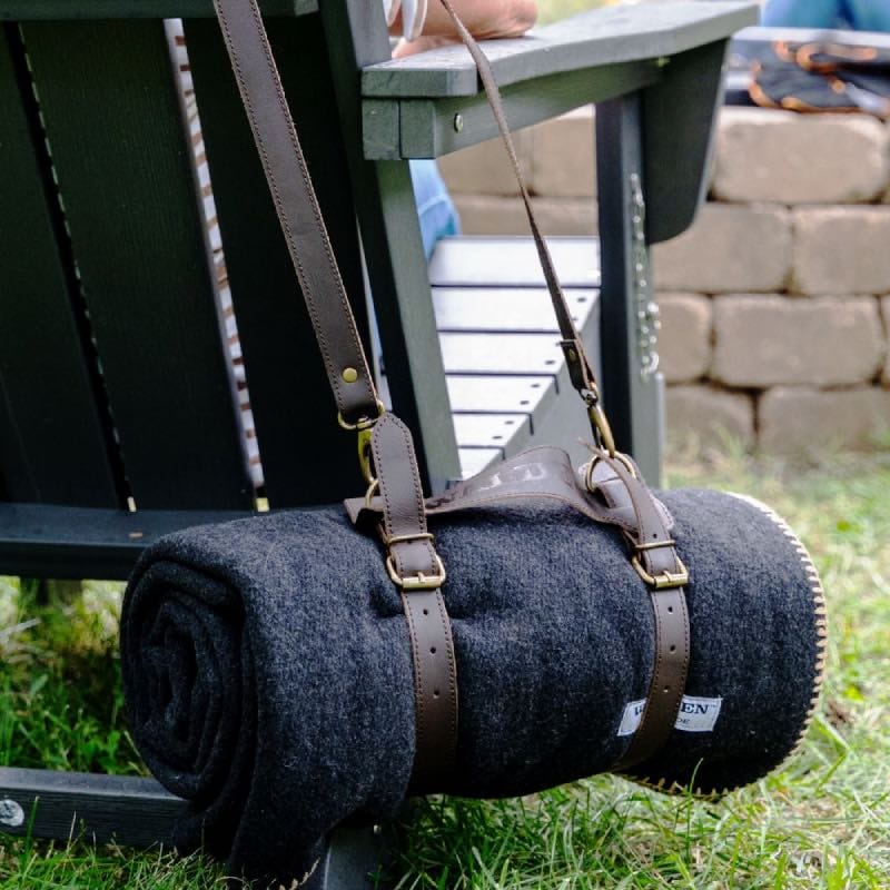 Walden fire retardant blanket is suspended by the fire pit with a leather strap from a fire pit chair.